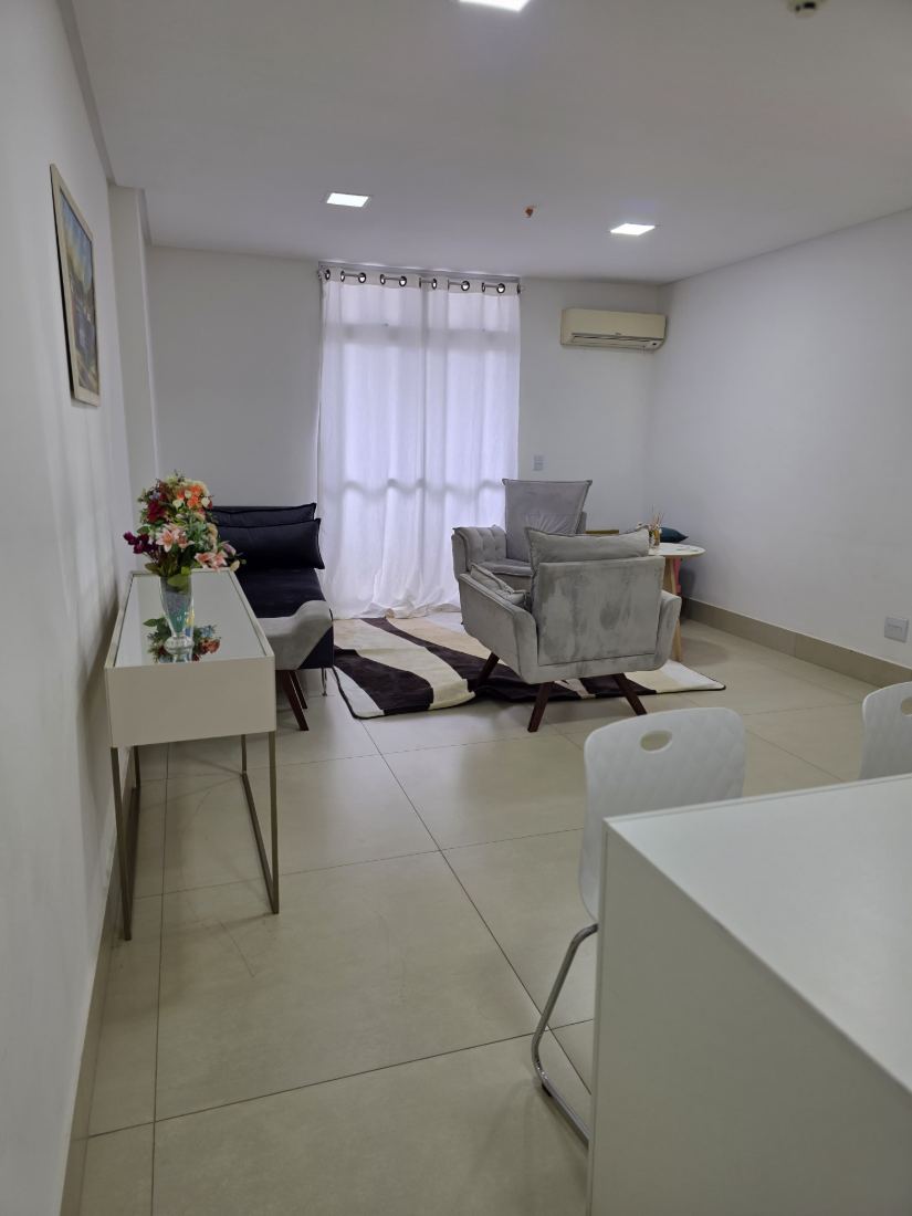Vista geral do consultório, com mesa, poltronas e janela ampla